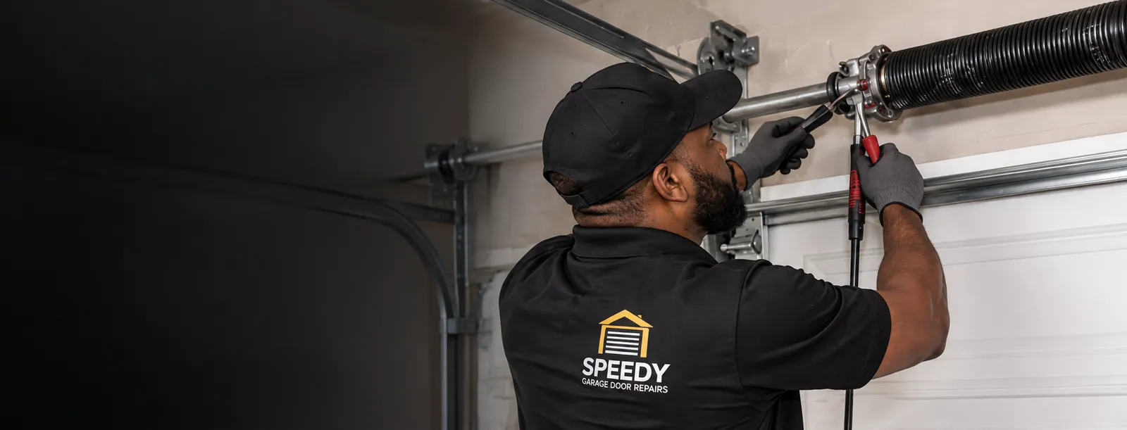 Black technician working on garage door spring replacement
